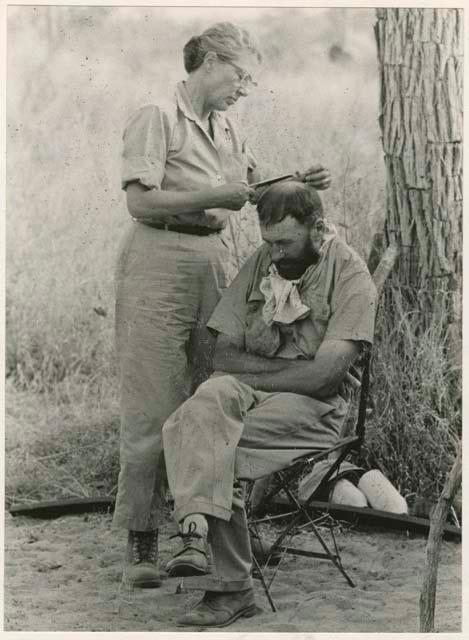 [No folder title]: Lorna Marshall cutting Robert Story's hair (print is a cropped image)