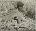 Digging for roots: Woman holding the stem of an edible root, picking it out from the grass (print is a cropped image)