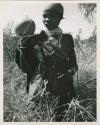 Women on gathering trips: ≠Nisa standing and holding a tsama melon (print is a cropped image)