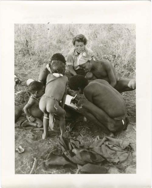 Berry picking: Man (possibly "Gao Medicine") imitating Elizabeth Marshall Thomas writing in her notebook with her pen, with "/Gao Lame" and children watching him (print is a cropped image)