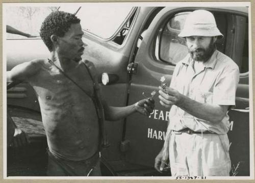 [No folder title]: "Gao Medicine" standing near the expedition truck with Robert Story examining a plant