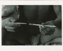 [No folder title]: Person's hands holding an arrowpoint (print is a cropped image)