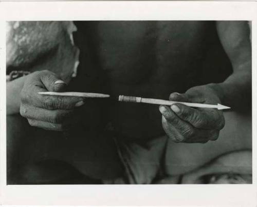 [No folder title]: Person's hands holding an arrowpoint (print is a cropped image)