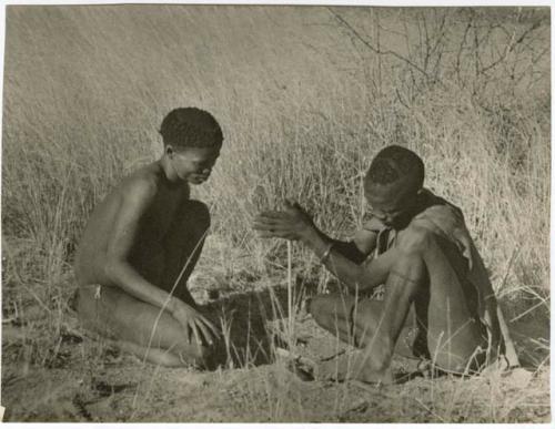 [No folder title]: ≠Gao (headman of Band 3) and "/Qui Hunter" making a fire, with ≠Gao twirling the "male" stick in the notch of the "female" stick, steadying it with his digging stick and his foot (print is a cropped image)