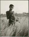 "Boys playing at hunting": /Gishay holding a guinea fowl that he shot through the neck with an arrow (print is a cropped image)