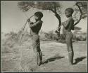 Hunters walking, standing: Two boys standing and holding bows and arrows (print is a cropped image)