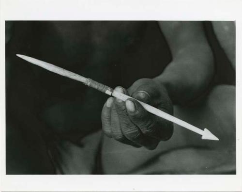 Hunting equipment: Person's hands an arrowpoint attached to connecting link (print is a cropped image)