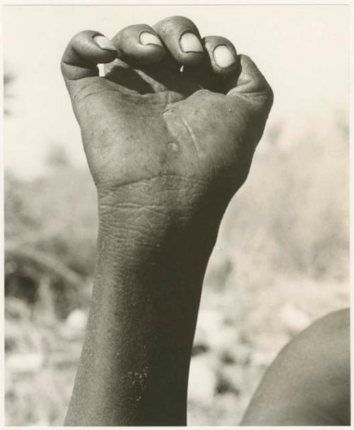 "The hunting hand signs": Person demonstrating the hunting hand signal for an unidentified animal (print is a cropped image)