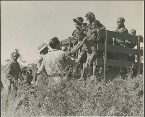 Women and children being helped down from the expedition truck by Heinrich Neumann and Ernst Westphal (print is a cropped image)