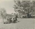 Two medicine men in deep trance (left), and people resting from a curing dance under tree