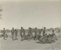 Group of men performing a curing dance, cutting across a circle of women