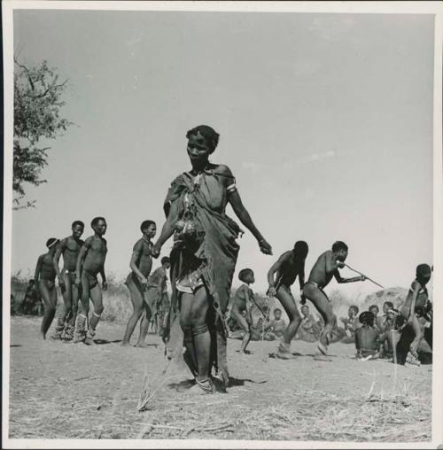 Woman dancing in the foreground, with a group of people behind