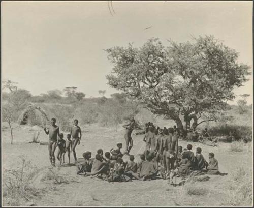 Men dancing crossing through circle of women;  two boys dancing with the men