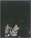 Laurence Marshall and John Marshall sitting by the fire at night (print is a cropped image)
