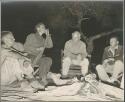 John Marshall, Lorna Marshall, Laurence Marshall, and Ernst Westphal sitting around the fire

