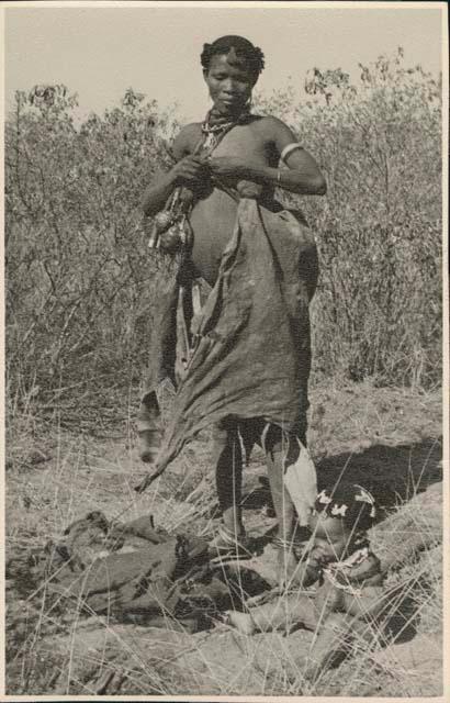 Woman tying her kaross to make pouch for carrying veldkos (print is a cropped image)


