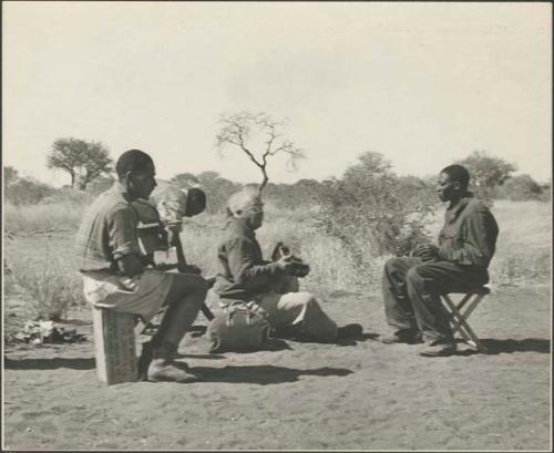 Laurence Marshall sitting in camp with members of the staff
