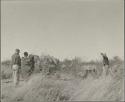 Group of people sitting in grass, with John Marshall filming them