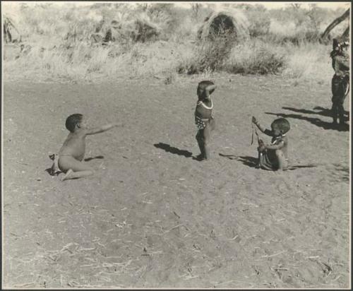 Three children playing in an open place, with skerms in the background