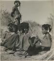 Girls seated close together, one playing a //guashi (print is a cropped image)