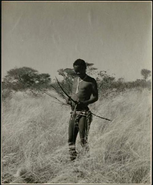 Man with bow and arrow walking in the grass
