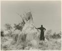 "Ant hills": Man standing beside an ant-hill (print is a cropped image)