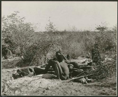 "Boys' fire": Group of boys sitting and lying down near a bed of ashes in their dwelling place (print is a cropped image)