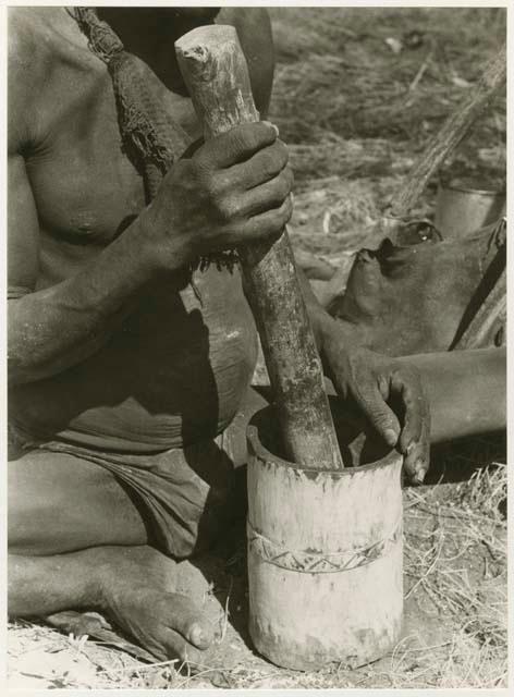 "Mortar and pestle": Person using a mortar and pestle, close-up (print is a cropped image)