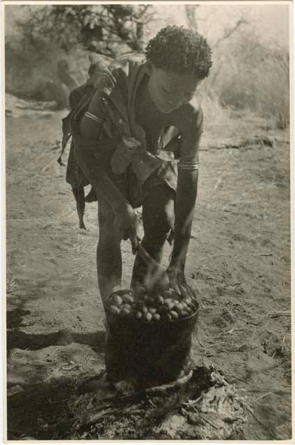 [No folder title]: /Naoka ("Gao Medicine's" wife) cooking a pot full mangetti nuts on a fire (print is a cropped image)