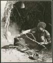 [No folder title]: "/Qui Hunter" cooking meat on a fire in an Ovambo pot (print is a cropped image)