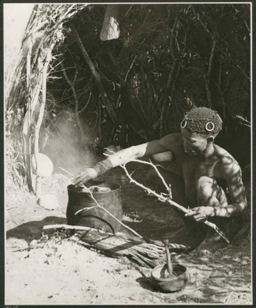 [No folder title]: "/Qui Hunter" cooking meat on a fire in an Ovambo pot (print is a cropped image)