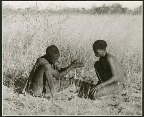 "Firemaking": ≠Gao (headman of Band 3) and "/Qui Hunter" making a fire, with ≠Gao twirling the "male" stick in the notch of the "female" stick, steadying it with his digging stick and his foot (print is a cropped image)