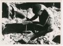 "Firemaking": Man making a fire (print is a cropped image)