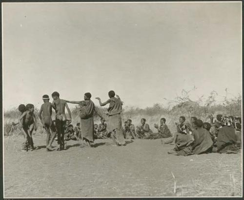 "Daytime dance at Gautscha": Two women and boys dancing, with a group of women sitting and clapping at the beginning of a dance (print is a cropped image)