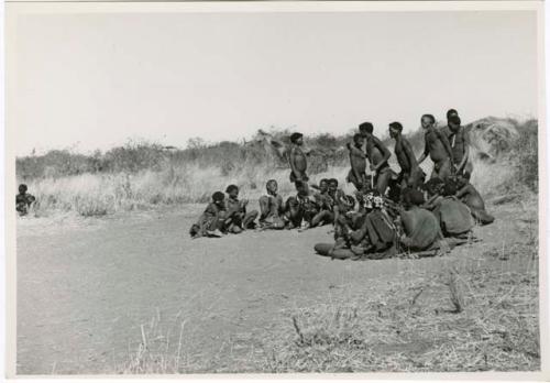 "Daytime dance at Gautscha": Men dancing, cutting through a circle of women sitting and clapping (print is a cropped image)