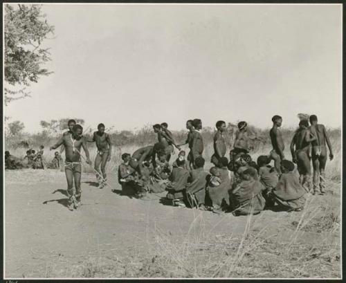 "Daytime dance at Gautscha": Men dancing, including "/Gao Medicine" whose hands are being held behind him by another man (print is a cropped image)