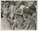 Group of women huddled, including a woman nursing her baby


