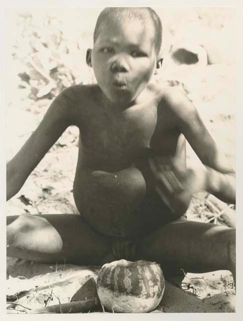 Boy eating tsama melon, seated

