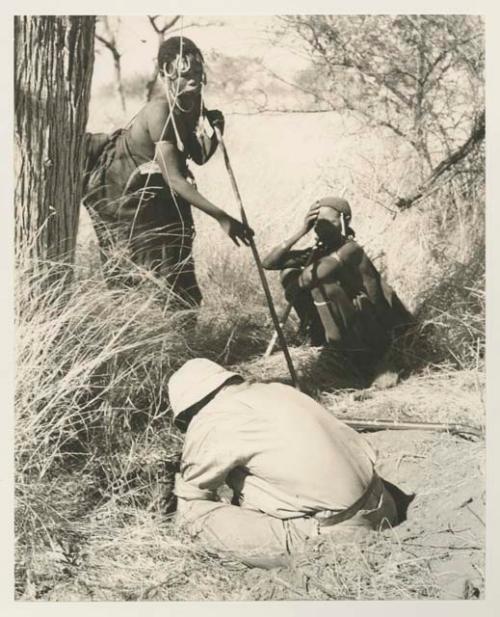 //Kushay standing and another woman sitting next to Robert Story pulling out a root


