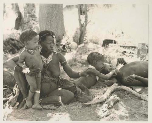 Debe standing by his mother holding mealies, and /Gaishay giving "≠Gao Lame" a bite of mealies