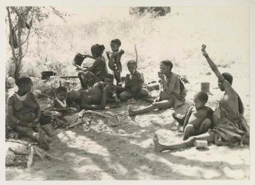 Group of people sitting including Debe, "≠Gao Lame," Norna, /Gaishay and !U; //Khuga (wife of "Crooked /Qui," and daughter of "/Gao Medicine") with her daughter, Bau, in the right corner