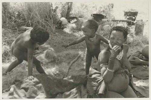 Di!ai sitting, with her son, Debe, standing behind her and smiling at another child