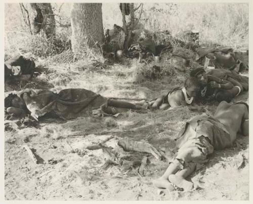 Group of people resting under a tree, including //Khuga, Bau, /Gaishay, Di!ai and /Naoka, and a bowl of tsi
