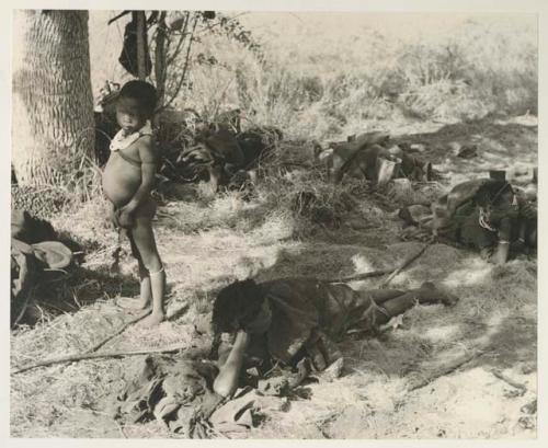 Group of people resting under a tree, including //Khuga, Bau, Di!ai and /Naoka, and Di!ai's son /Gaishay standing