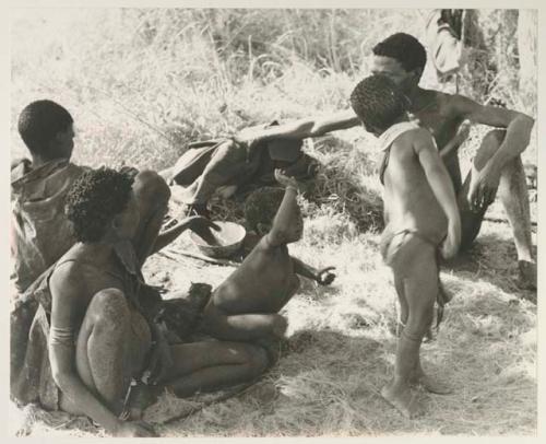 Group of people sitting, including /Naoka ("Gao Medicine's" first wife) with her granddaughter Bau and Gao Medicine, and /Gaishay standing

