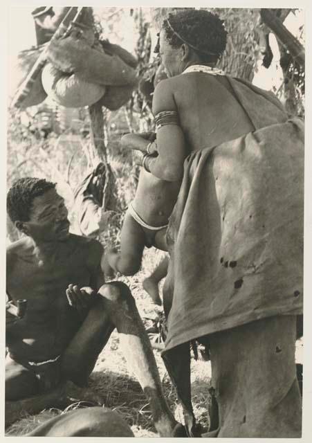 "Gao Medicine" sitting, and Di!ai standing and picking Debe up from his shoulder
