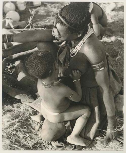 Di!ai sitting, with Debe on her knee about to nurse
