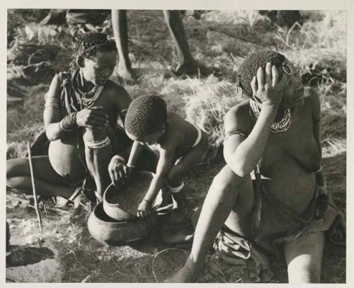 Di!ai and !U sitting, and Debe playing with a broken bowl