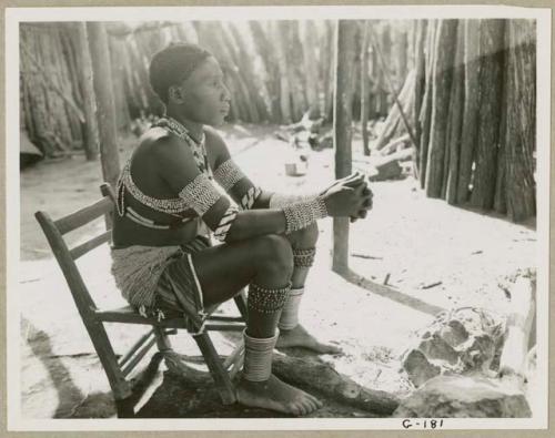 Makiena (Muremi's wife) sitting in her kraal, wearing her Kwangali beads and copper anklets (print is a cropped image)