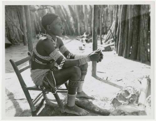 Makiena (Muremi's wife) sitting in her kraal, wearing her Kwangali beads and copper anklets (print is a cropped image)